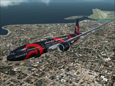 Team Alinghi Boeing 777-200 flying over a coastal city.