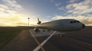 A U.S. Air Force KC-10 Extender sits on a taxiway at sunrise with long shadows and partly cloudy skies.