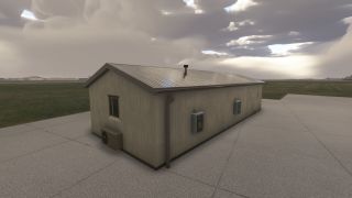 A small utility building with a metal roof and electrical boxes stands on a concrete pad beside a grassy airfield under cloudy skies.
