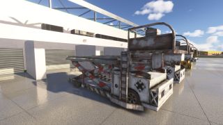 Several weathered airport scissor lift vehicles are parked on a wet concrete ramp in front of a white building with closed garage doors.