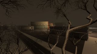Bare tree branches frame a nighttime airport scene with snow-covered ground, illuminated hangars, and distant runway lights visible in the background.