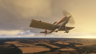 A white, red-striped propeller aircraft with fixed landing gear flies above patchwork farmland beneath golden clouds.