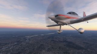 A silver single-engine airplane with red stripes and fixed landing gear flies above a sprawling city beneath a pink and orange sky.