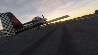 A black single-engine aircraft with a checkered tail and red dragon emblem sits on airport pavement beneath a golden sky.