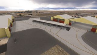 Several military jets sit beneath a long apron canopy between yellow hangars with red doors, surrounded by taxi markings and dry terrain.