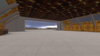 An empty hangar has exposed roof beams, a concrete floor, and a wide doorway overlooking an apron beneath cloudy skies.