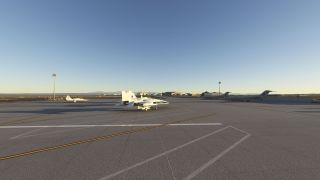 NASA-marked aircraft sit on a sunlit airport apron, with a twin-tail jet in the foreground and hangars beyond.