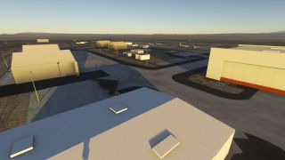 Large hangars surround concrete aprons, with a dark flying-wing aircraft parked in shadow and several other aircraft visible farther away.