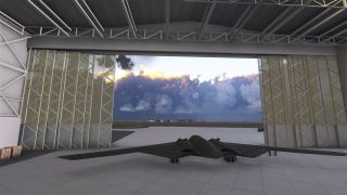 A dark flying-wing bomber rests inside an open hangar, with landing gear extended and sunlit clouds above the apron outside.