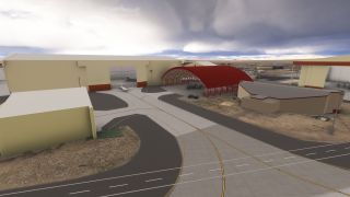 Beige hangars and a red arched aircraft shelter surround marked taxiways, with parked aircraft beneath heavy clouds.