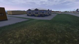 A two-story building with blue trim stands beside a grassy verge, with parked cars and an airport control tower beyond.