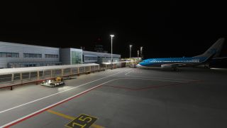 A KLM jet sits beside a floodlit terminal at night, with ground service equipment and stand marking 15 visible on the apron.