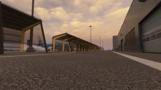 A KLM airliner sits behind yellow-supported shelters beside a gray airport building under an orange, cloud-filled sky.