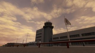 An airport control tower rises above adjoining buildings, with red roadside barriers and a white flag beneath a golden, cloud-filled sky.