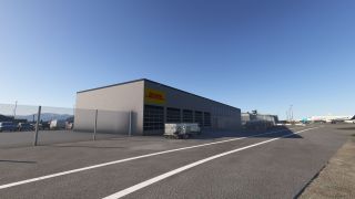 A DHL cargo building stands beside a fenced parking area, with cargo carts outside and passenger aircraft on the apron beyond.