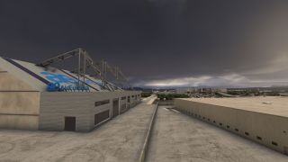 An Air Europa hangar with exposed roof trusses stands beside a paved service area and low airport buildings under dark clouds.