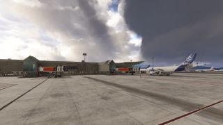 An Airbus A310 stands beside terminal jet bridges on a marked concrete apron beneath large, dark clouds.