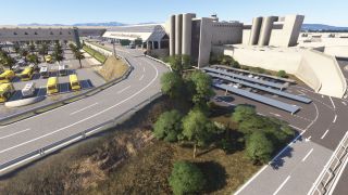 Palma de Mallorca Airport’s terminal overlooks curving access roads, rows of yellow and white buses, and covered parking spaces.