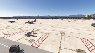 Several propeller aircraft occupy numbered apron stands, with red safety markings, ground vehicles, terminal buildings, and mountains beneath clear skies.