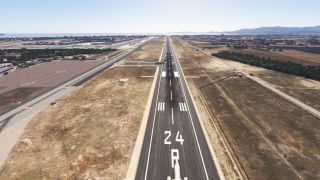 Runway 24R extends toward the coast, with aircraft near taxiway intersections, terminal aprons to the left, and dry fields alongside.