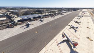 Passenger jets occupy terminal gates and remote stands beside a broad taxiway, with a red-tailed Jet2.com aircraft in the foreground.