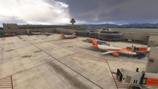 Two easyJet airliners stand beside terminal jet bridges, with ground equipment, a control tower, and distant mountains beneath heavy clouds.
