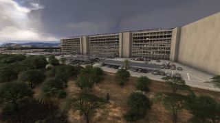 A multistory parking garage overlooks covered parking rows, numerous cars, and scattered trees beneath a dark, cloudy sky.