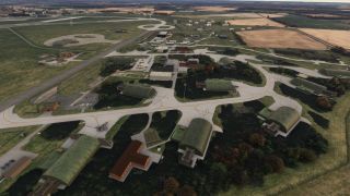An aerial view shows green arched aircraft shelters, interconnected taxiways, parked aircraft, and support buildings surrounded by fields.