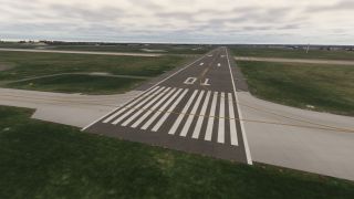 Runway 10 extends across grassy airfield terrain beneath overcast skies, with white threshold stripes and intersecting yellow taxiway lines.