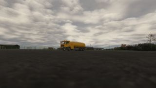 A yellow tanker truck sits on an airport apron beside perimeter fencing and low buildings beneath extensive gray clouds.