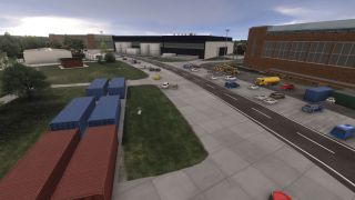 A road runs between industrial buildings, parked cars, and a yellow tanker truck, with red and blue shipping containers nearby.