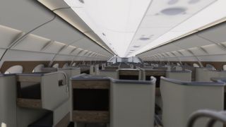 An aircraft cabin contains rows of partitioned seats with black entertainment screens, woodgrain trim, oval windows, and closed overhead bins.