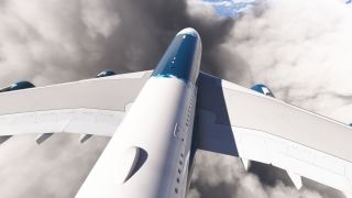 A blue-and-white airliner flies among thick clouds, viewed from above with broad wings and engine nacelles visible.