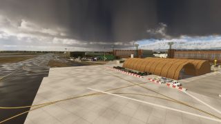 An airport apron features intersecting yellow taxi lines, arched brown shelters, ground equipment, and floodlight towers beneath dark clouds.