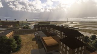 Brick airport buildings surround a grassy courtyard, with hangars, taxiways, and a distant aircraft beneath sunlit clouds.