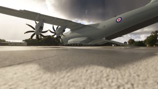 A gray RAF transport aircraft sits on the apron with stationary propellers, extended landing gear, and a lowered rear cargo ramp.
