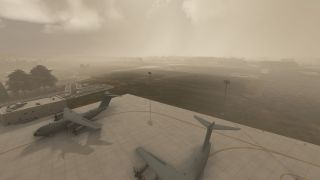 Two gray military turboprop transports sit on a concrete apron beside airport buildings, with runways fading into dense haze.