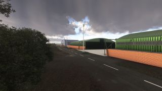 Green hangars with brick lower walls line a marked service road beside dense trees under dark clouds.