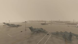 Several gray military transport aircraft sit on marked apron stands, with propellers, ground vehicles, and tall light poles visible through haze.