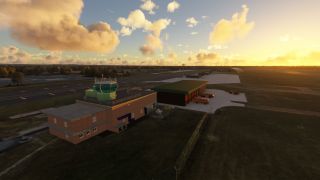 A brick airport control building stands beside a fire station with red emergency vehicles, while parked aircraft sit beneath golden clouds.