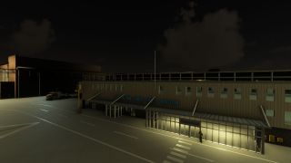 The Royal Air Force Brize Norton terminal stands at night with an illuminated departure entrance, apron markings, and parked ground vehicles.