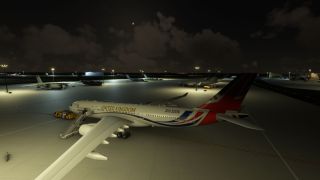 A Royal Air Force jet with Union Jack tail markings sits on a floodlit apron at night beside boarding stairs and a tug.