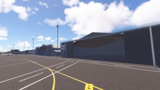 Large open hangars line an airport apron with yellow taxiway markings, white boundary lines, tall floodlights, and small parked aircraft.