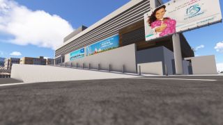 A large building with horizontal louvers stands beside a paved road, with airline advertisements and an elevated Air Tahiti Nui billboard.