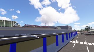 Tahiti Faa'a Airport’s terminal displays red rooftop lettering above a covered walkway with blue columns beside a marked access road.