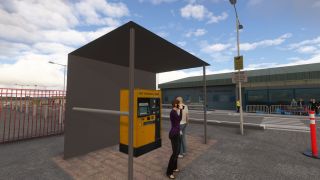Two people stand beside a sheltered yellow parking payment machine outside an airport terminal, with a pedestrian crossing and luggage trolleys nearby.