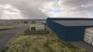 A white Air BP fuel tank stands beside blue corrugated hangars, with a fenced parking area beyond under cloudy skies.