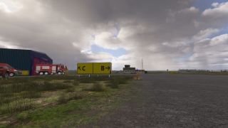 Yellow taxiway signs point toward C and B beside a fire station, parked emergency vehicles, and a control tower under cloudy skies.