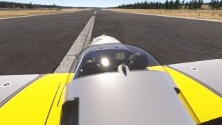A yellow-and-gray light aircraft sits on a runway, viewed from behind its bubble canopy with digital cockpit displays visible.