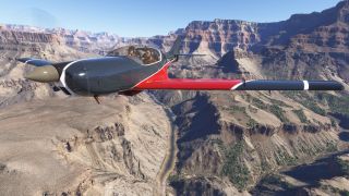 A dark gray and red single-engine aircraft with two occupants flies above a winding river between layered canyon cliffs.